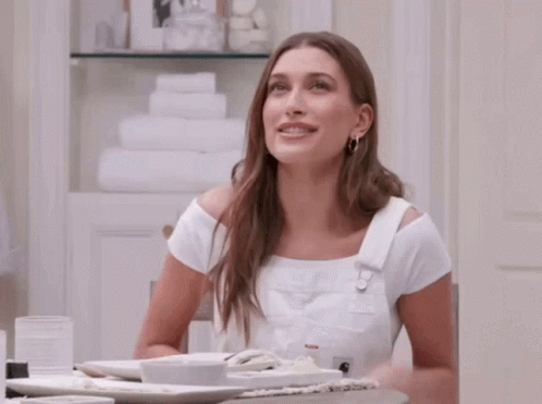 A Woman Is Sitting At A Table With Plates Of Food On It GIF