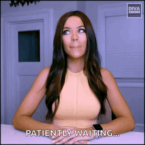 A Woman Is Sitting At A Table With The Words Patiently Waiting On The Screen GIF