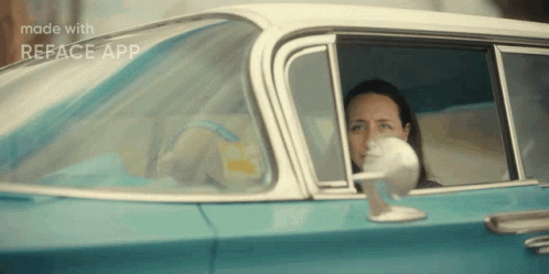 A Woman Is Sitting In A Blue And White Car With Her Head Out The Window . GIF