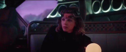 A Woman Is Sitting In A Car With A Crown On Her Head And A Lamp . GIF