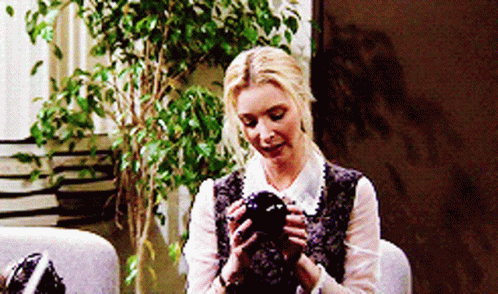 A Woman Is Sitting In A Chair Holding A Black Object GIF