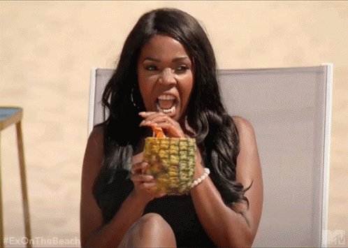 A Woman Is Sitting In A Chair Holding A Pineapple And Drinking From It . GIF