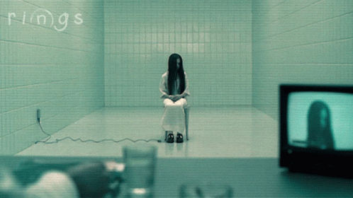 A Woman Is Sitting In A Chair In A Room With The Word Rings Written On The Wall GIF