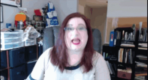 A Woman Is Sitting In A Chair In Front Of A Bookshelf With A Blue Bag That Says ' Blue ' On It GIF