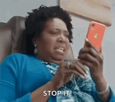 a woman is sitting in a chair looking at her cell phone and making a funny face .