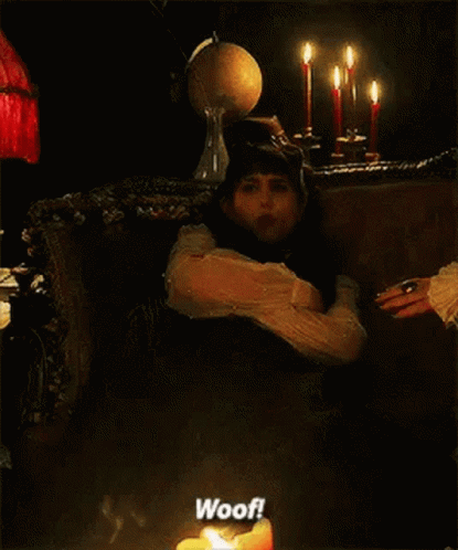 a woman is sitting in a chair next to a lit candle and says woof