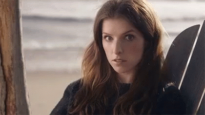 A Woman Is Sitting In A Chair On The Beach With A Surfboard . GIF