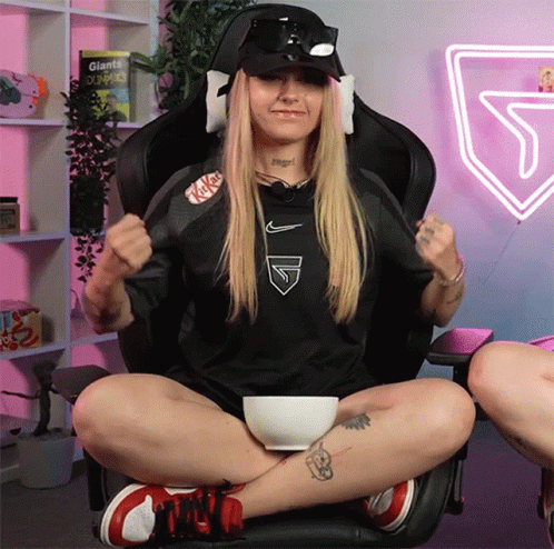 A Woman Is Sitting In A Chair With A Bowl Of Food In Her Lap GIF