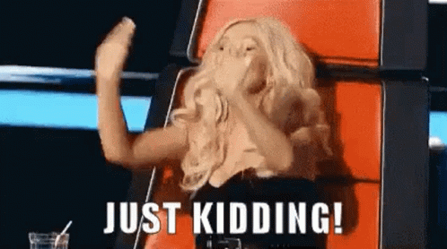 A Woman Is Sitting In A Chair With Her Hands In The Air And The Words `` Just Kidding ! '' Above Her . GIF