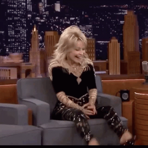 a woman is sitting in a chair with her legs crossed and laughing