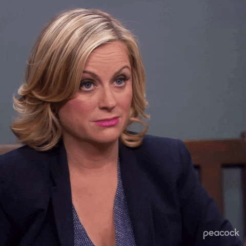 A Woman Is Sitting In A Chair With Peacock Written On The Bottom GIF