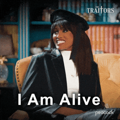 A Woman Is Sitting In A Chair With The Words " I Am Alive " On The Screen GIF