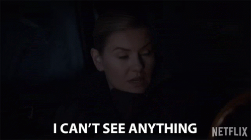 A Woman Is Sitting In A Dark Room And Says `` I Can T See Anything '' . GIF