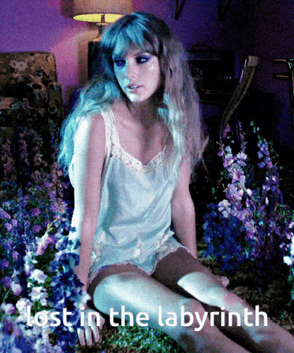 A Woman Is Sitting In A Field Of Flowers With The Words Lost In The Labyrinth Below Her GIF