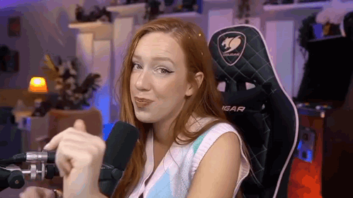 A Woman Is Sitting In A Gaming Chair In Front Of A Microphone And Making A Funny Face . GIF