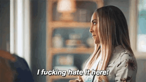 A Woman Is Sitting In A Living Room Talking To A Man And Says `` I Fucking Hate It Here ! '' GIF
