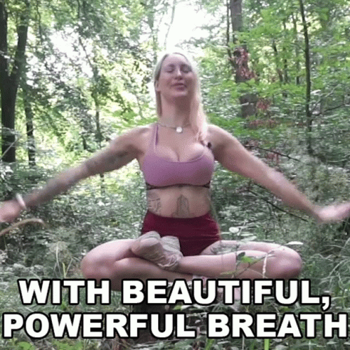 A Woman Is Sitting In A Lotus Position In The Woods With Her Eyes Closed . GIF