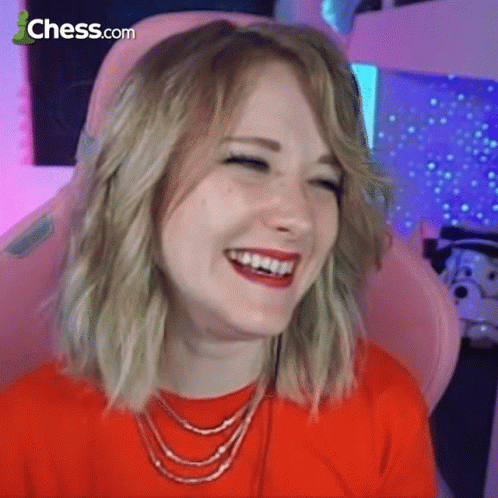 A Woman Is Sitting In A Pink Chair And Laughing With Chess.com In The Corner GIF