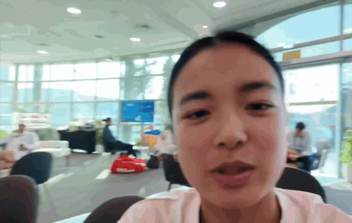 A Woman Is Sitting In A Room With A Lot Of Windows GIF
