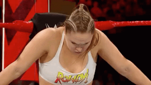 A Woman Is Sitting In A Wrestling Ring With Her Arms Outstretched . GIF