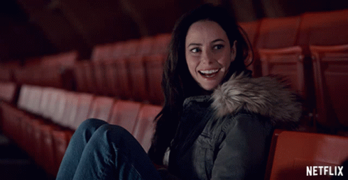 A Woman Is Sitting In An Auditorium With A Netflix Logo In The Background GIF