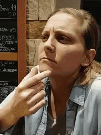 A Woman Is Sitting In Front Of A Chalkboard That Says Brown 4.9 On It GIF