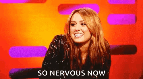 A Woman Is Sitting In Front Of A Colorful Background And Smiling . GIF