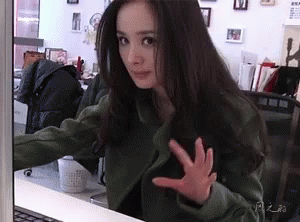 A Woman Is Sitting In Front Of A Laptop Computer And Making A Funny Face . GIF