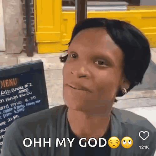 A Woman Is Sitting In Front Of A Menu Board And Says " Ohh My God " GIF