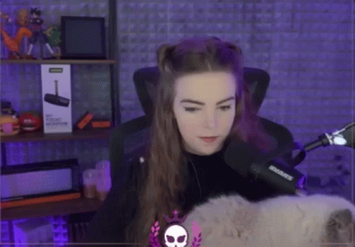 A Woman Is Sitting In Front Of A Microphone And A Box That Says ' Shure ' On It . GIF