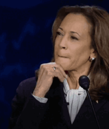 A Woman Is Sitting In Front Of A Microphone With Her Hand On Her Chin And A Ring On Her Finger . GIF