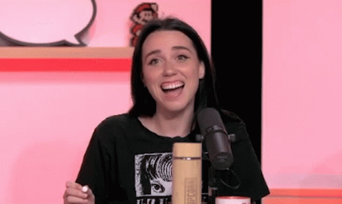A Woman Is Sitting In Front Of A Microphone With Her Mouth Open And Smiling . GIF