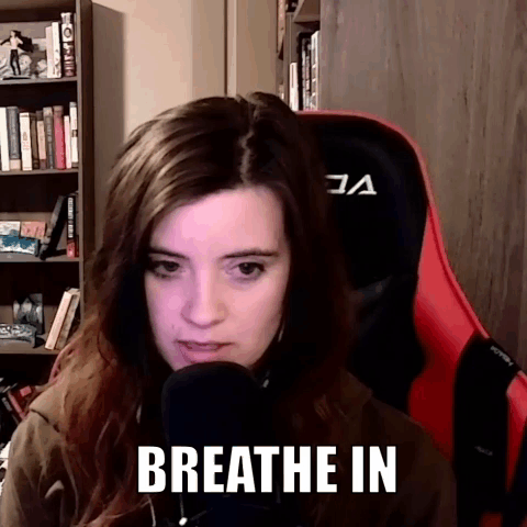 A Woman Is Sitting In Front Of A Microphone With The Words Breathe In On Her Face . GIF