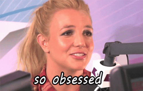 A Woman Is Sitting In Front Of A Microphone With The Words So Obsessed Below Her GIF