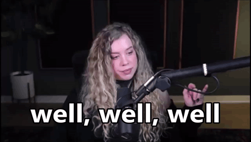 A Woman Is Sitting In Front Of A Microphone With The Words `` Well , Well , Well '' . GIF