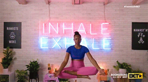 A Woman Is Sitting In Front Of A Neon Sign That Says Inhale Exhale GIF