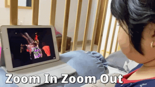 A Woman Is Sitting In Front Of A Tablet That Says Zoom In Zoom Out On The Bottom GIF