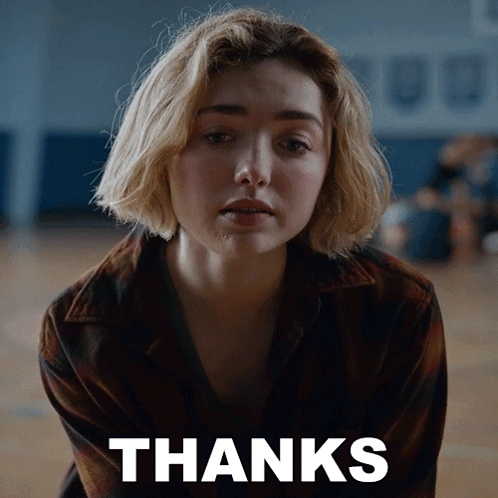 A Woman Is Sitting In Front Of A Thanks Sign GIF