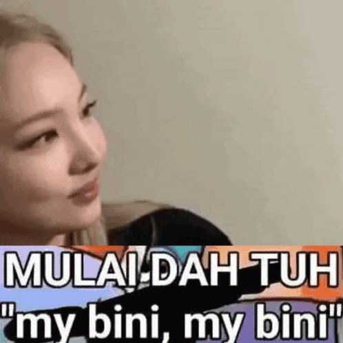 A Woman Is Sitting In Front Of A Wall With A Sticker That Says Mulai Dah Tuh My Bini My Bini . GIF