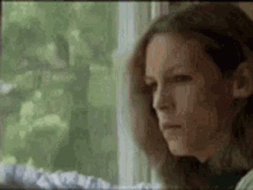 a woman is sitting in front of a window looking out .