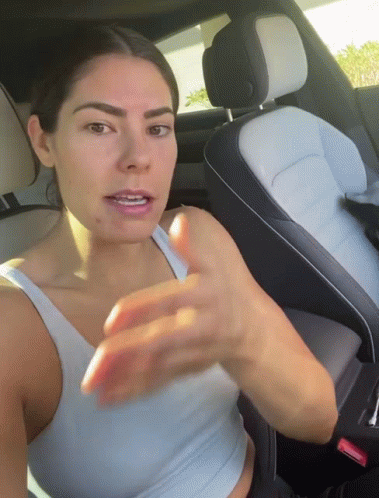 A Woman Is Sitting In The Back Seat Of A Car GIF