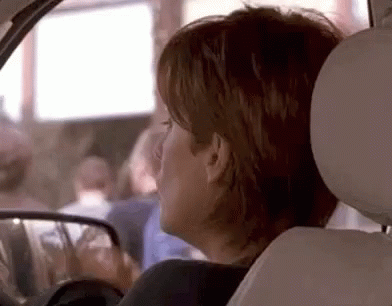 A Woman Is Sitting In The Back Seat Of A Car . GIF