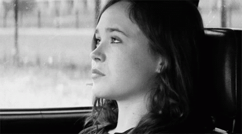 A Woman Is Sitting In The Back Seat Of A Car And Looking Out The Window . GIF
