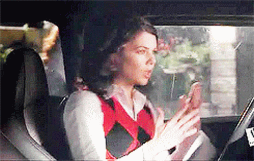 A Woman Is Sitting In The Back Seat Of A Car Looking At Her Phone . GIF