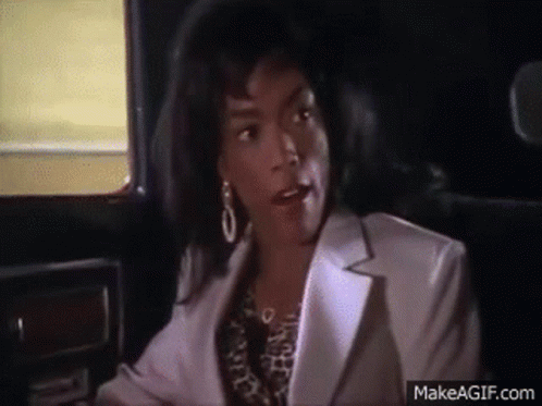 A Woman Is Sitting In The Back Seat Of A Car Talking To Someone . GIF