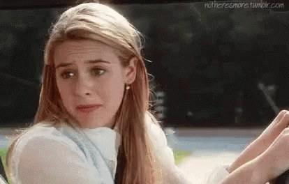 A Woman Is Sitting In The Driver 'S Seat Of A Car And Looking At Her Phone . GIF