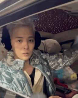 A Woman Is Sitting In The Driver 'S Seat Of A Car Wearing Ear Muffs . GIF