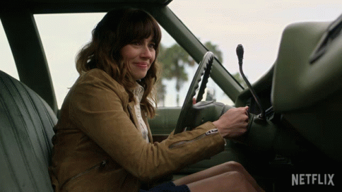 A Woman Is Sitting In The Driver 'S Seat Of A Car With The Netflix Logo On The Dashboard GIF