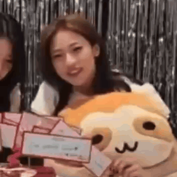 A Woman Is Sitting Next To A Stuffed Animal And Holding A Sign . GIF