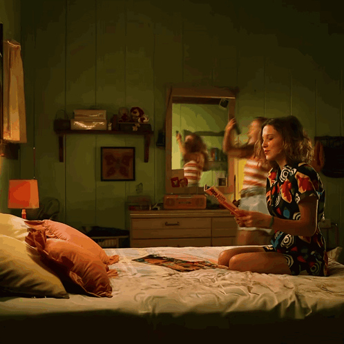 A Woman Is Sitting On A Bed Reading A Book Called " A Brief History Of The World " GIF